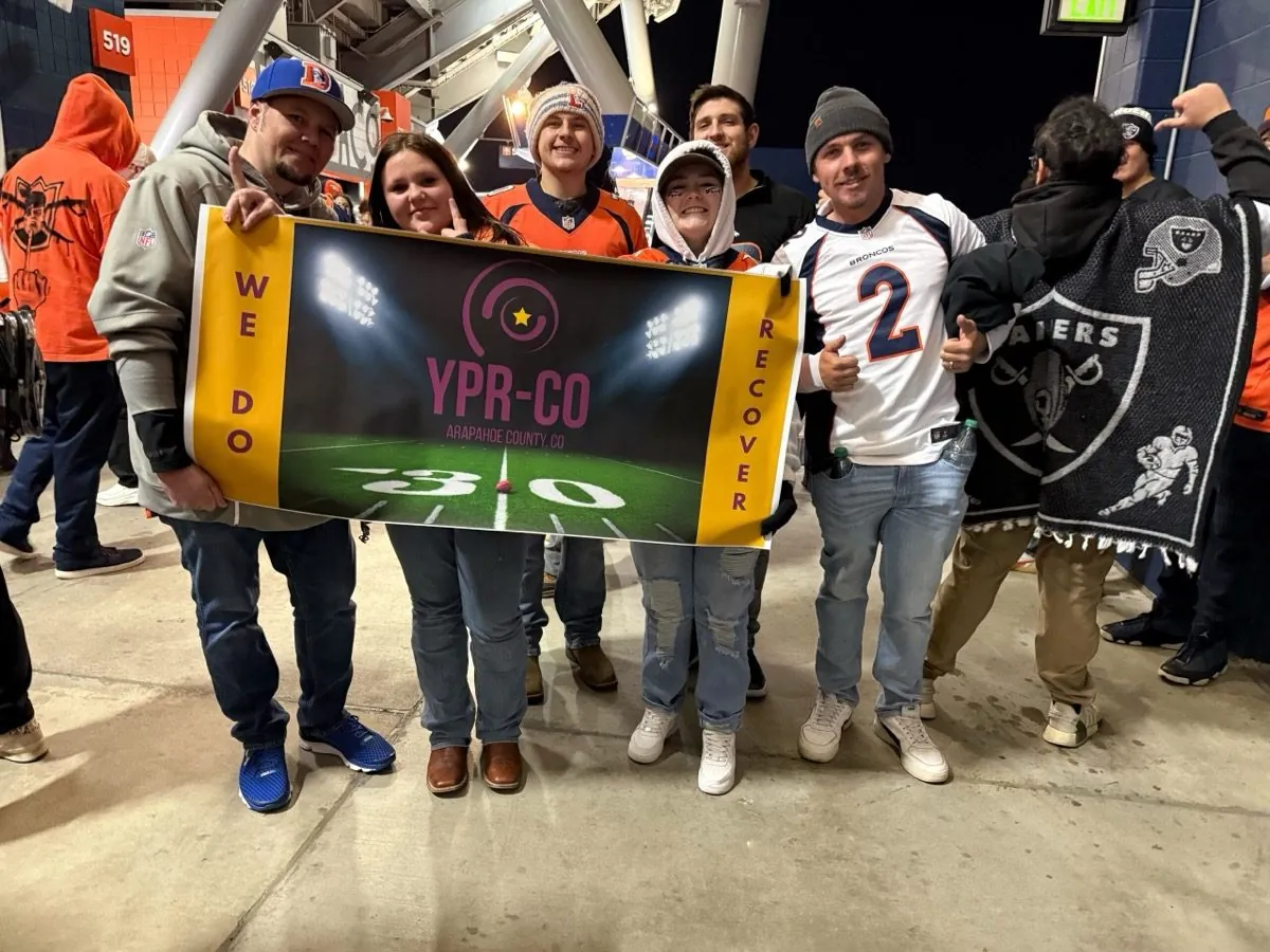 YPR chapter members holding a WE DO RECOVER banner at a Broncos game